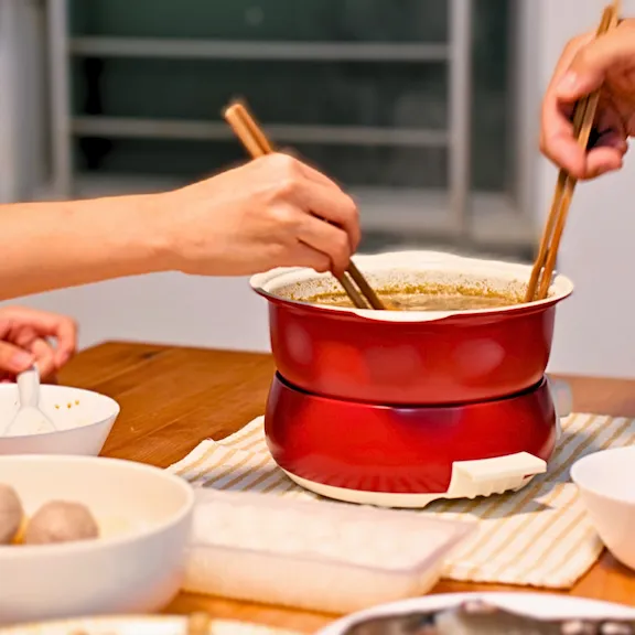 Hands of two people eating soup noodles